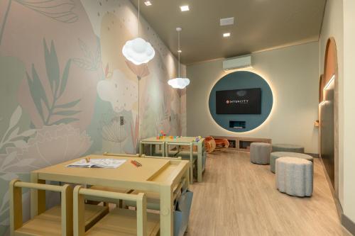 a waiting room with tables and a tv on a wall at Intercity Porto Alegre Aeroporto in Porto Alegre