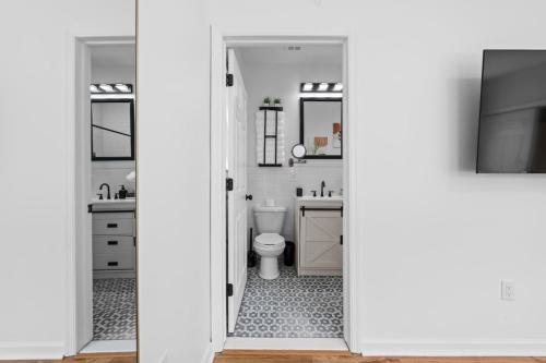 a white bathroom with a toilet and a television at NYC 20min Free Parking Hot Tub EWR 15min in Bayonne