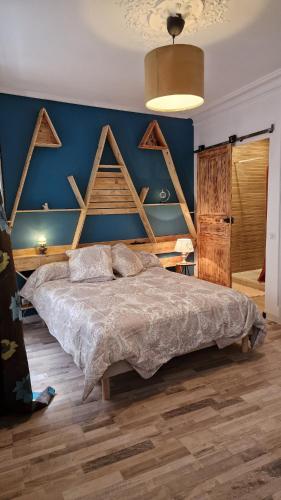 une chambre avec un grand lit et un mur bleu dans l'établissement l'appart, à Thiers