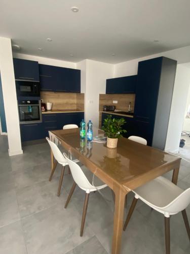 - une cuisine avec une table en bois et des chaises blanches dans l'établissement maison de village, à Abrest