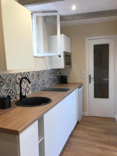 une cuisine avec des armoires blanches et un évier dans l'établissement Séjour authentique avec vue mer à Menton, à Menton