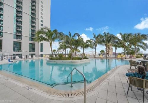 a large swimming pool with palm trees in a resort at Bright and Breezy 1 Bed Unit With Water and City Views in Miami