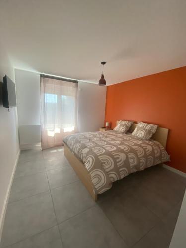 une chambre avec un lit avec un mur orange dans l'établissement maison de village, à Abrest