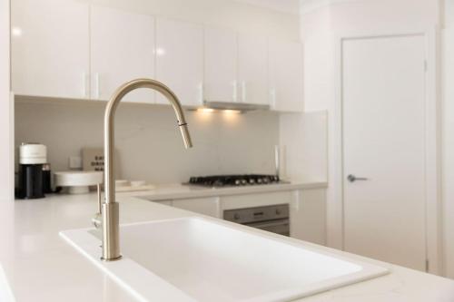 a white kitchen with a sink and a faucet at Coastal Cove in Budgewoi