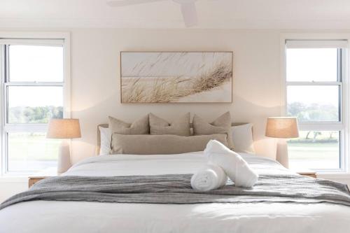 a white bedroom with a large bed with two windows at Coastal Cove in Budgewoi