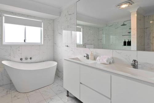 a white bathroom with a tub and a sink at Coastal Cove in Budgewoi