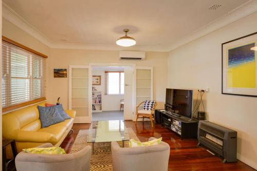 a living room with a couch and chairs and a tv at Pebbles by the Bay - Central Busselton in Busselton