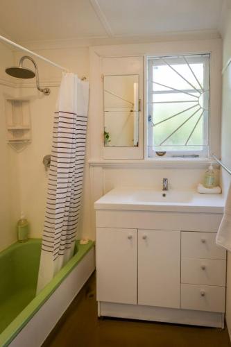 a bathroom with a sink and a tub and a window at Pebbles by the Bay - Central Busselton in Busselton