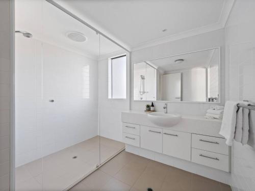 a white bathroom with a sink and a mirror at Seventh Heaven Surfside in Yallingup