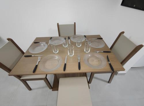 une table en bois avec des assiettes et des verres à vin dessus dans l'établissement Casa de Condomínio 350 mts da Praia, à Praia Grande