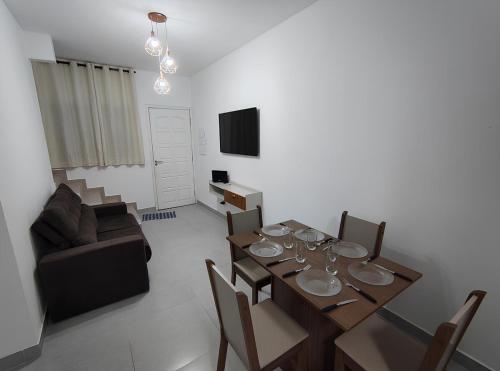 une salle à manger avec une table, des chaises et une télévision dans l'établissement Casa de Condomínio 350 mts da Praia, à Praia Grande