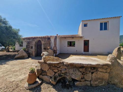 une maison avec un mur en pierre devant elle dans l'établissement Chambres d hôtes, calme et nature, à Pianottoli-Caldarello