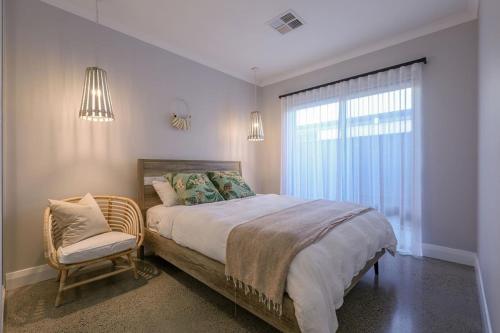 a bedroom with a bed and a chair and a window at Kawana Retreat - modern Dunsborough holiday haven. in Dunsborough