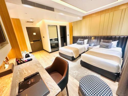 a hotel room with two beds and a desk at The Zabeer Dhaka in Dhaka