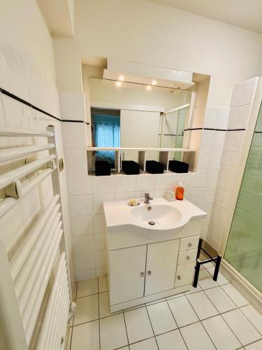 une salle de bain blanche avec un lavabo et un miroir dans l'établissement Beau T2, aperçu mer et accès plage, à Cavalaire-sur-Mer