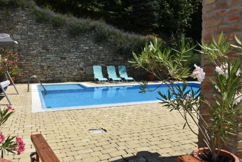 a swimming pool with two blue lounge chairs next to it at Ulbert Pince Panzió in Szederkény