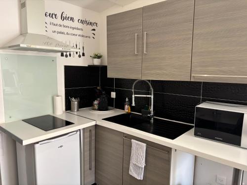 une cuisine avec un évier et un micro-ondes dans l'établissement Studio cosy avec jardin proche centre et plage, à Montpellier