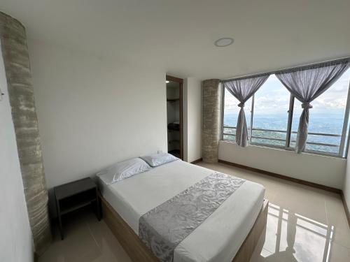 a bedroom with a bed and a large window at CENTRO historico y CC FUNDADORES in Manizales