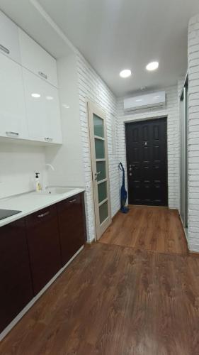 a kitchen with white cabinets and a wooden floor at VIP Apartments 9 in Odesa