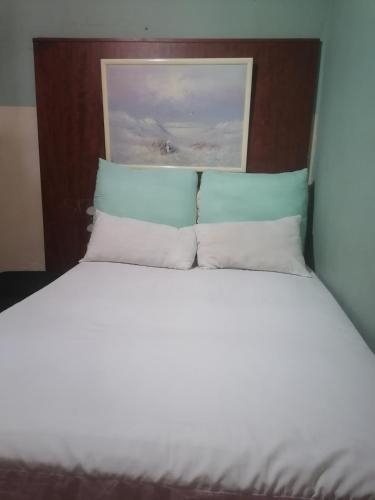 a large bed with white sheets and blue pillows at Valley Center Guest House in Johannesburg