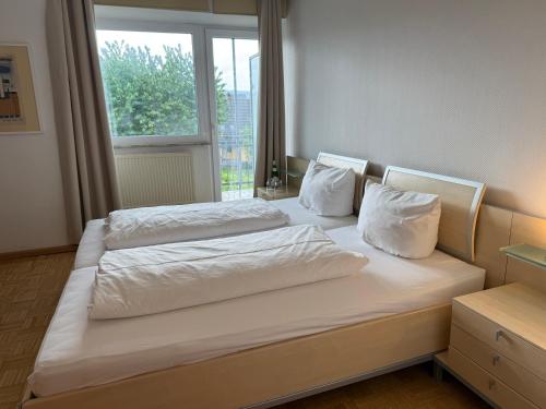 a bedroom with two beds with white sheets and a window at Hotel Villa Martino - zum Hirsch in Bad Säckingen