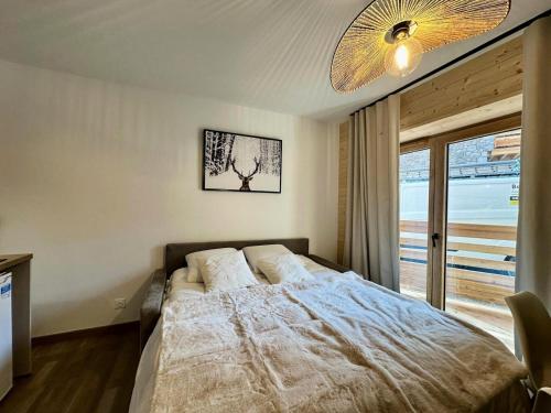 una camera da letto con un letto e una grande finestra di Résidence Le Living Stone B - COCON A LA MONTAGNE, CENTRE VARS-Tout inclus MAE-7691 a Vars