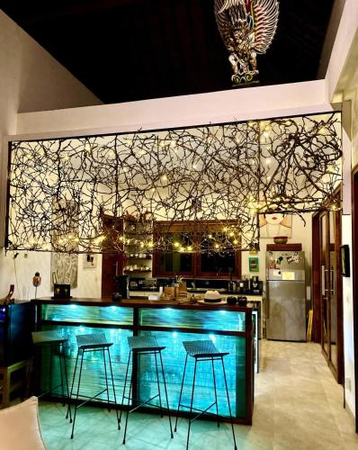 a bar in a kitchen with three stools at Wake up to the Sea of Bali Beachfront luxury plus in Singaraja