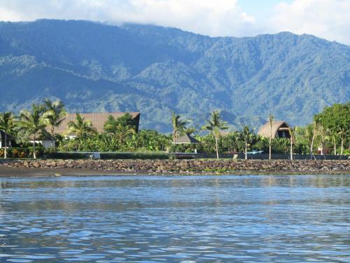 a body of water with houses and mountains in the background at Wake up to the Sea of Bali Beachfront luxury plus in Singaraja