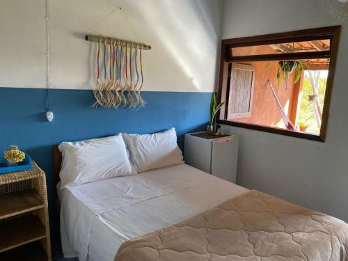 a bedroom with a white bed and a window at Chalés Vale Encantado - Serra do Cipó in Jaboticatubas