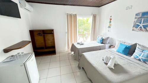 a white room with two beds and a window at Pousada Oceano Atlântico in Marau