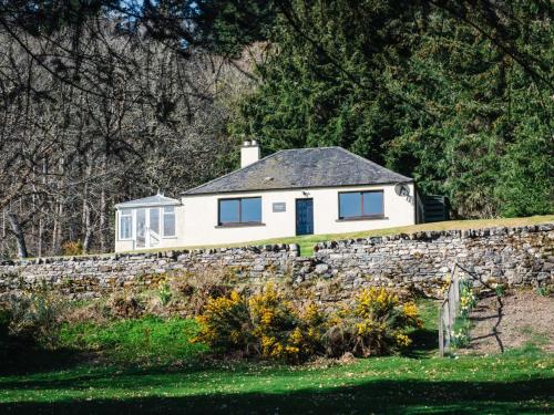 a white house on top of a stone wall at Holiday Home Farmburn Bothy by Interhome in Invermoriston