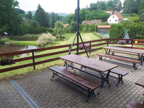 a group of picnic tables on a patio with a fence at Penzion Ztracený mlýn in Slapy