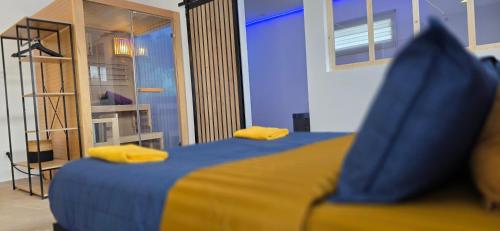 - une chambre avec un lit doté de draps bleus et d'oreillers jaunes dans l'établissement Le Rêve SPA Sauna, cinéma Colmar, à Muntzenheim