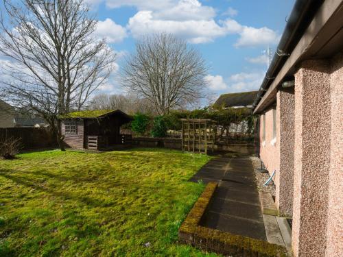 a garden next to a house with a sidewalk at Holiday Home Appletree by Interhome in Muir of Ord