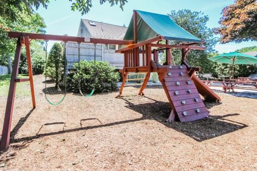 a playground with a slide and an umbrella at Holly Tree Resort in West Yarmouth