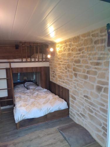 un lit dans une chambre avec un mur en pierre dans l'établissement Nuit insolite, à La Celle-sous-Gouzon