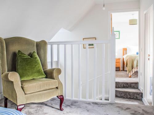 a chair with a green pillow in a room at Holiday Home The Old Post Office by Interhome in Saasaig