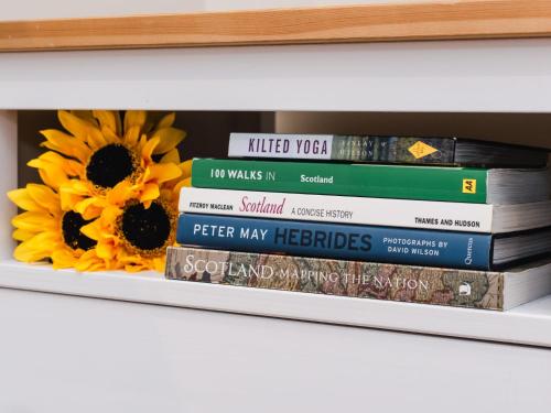 a stack of books on a shelf with sunflowers at Studio Wayside Loft by Interhome in Drumnadrochit