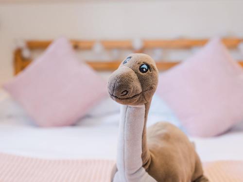 a stuffed ostrich head on a bed with white pillows at Studio Wayside Loft by Interhome in Drumnadrochit