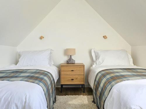 a bedroom with two beds and a night stand at Holiday Home The Longhouse by Interhome in Tokavaig