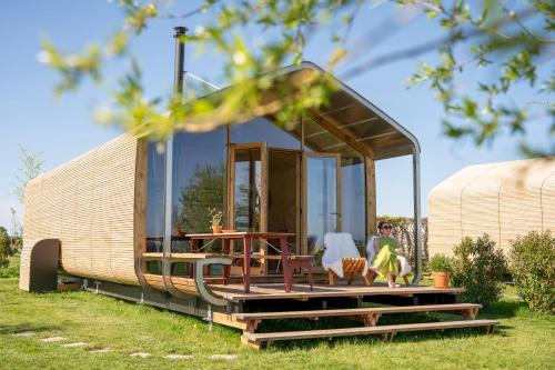 a tiny house on a trailer in the grass at Luxe Wikkelhouse met hottub 'Dompel' in Hoogwoud