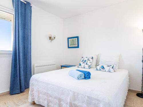 - une chambre avec un lit blanc et des rideaux bleus dans l'établissement Apartment Les Astérides by Interhome, à Hyères