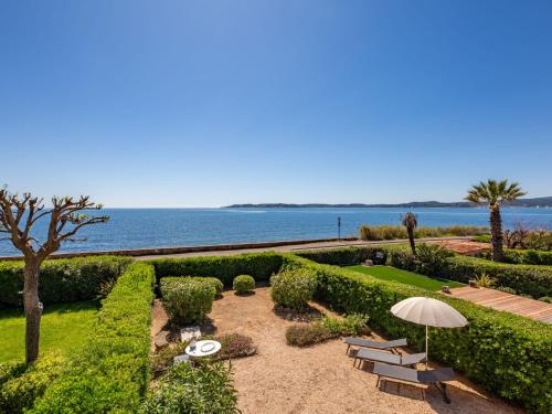 un jardin avec des bancs et un parasol et l'océan dans l'établissement Holiday Home El Cantarello-2 by Interhome, à Sainte-Maxime