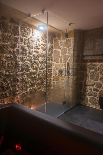 a bathroom with a glass shower in a stone wall at Villagio inn Suite & Spa in Soúlion