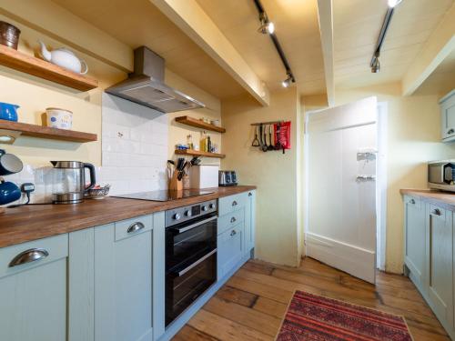 eine Küche mit weißen Schränken und einem Herd mit Backofen in der Unterkunft Holiday Home Seaforth Cottage by Interhome in Gorran Haven