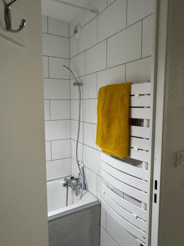 une salle de bain avec un lavabo, une baignoire et une serviette jaune dans l'établissement Le Boulouris - stylish T2, à Saint-Raphaël