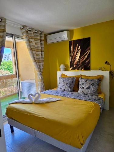 une chambre avec un lit avec un mur jaune dans l'établissement Le Boulouris - stylish T2, à Saint-Raphaël