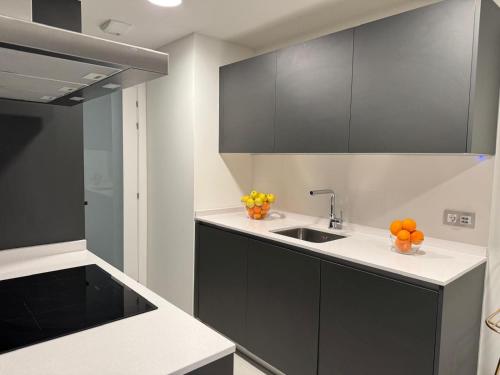 a kitchen with black cabinets and a sink at San Fermin Centro II in Pamplona