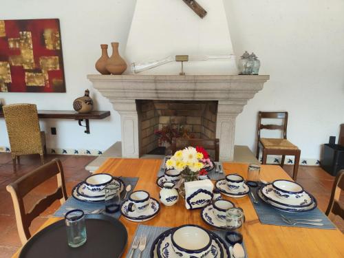 a dining room table with china on it with a fireplace at Casa de las Conchas Cuernavaca in Cuernavaca