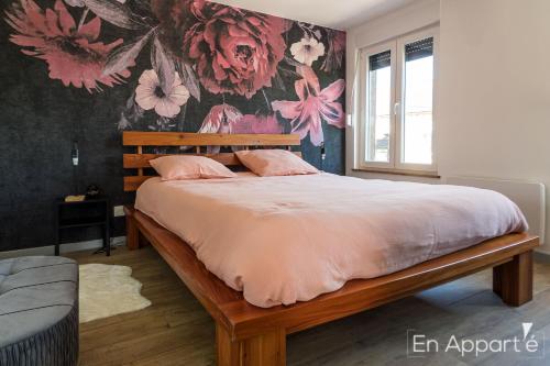 a bedroom with a bed with pink pillows and a floral wall at Appartement plein centre "En Appart'é" in Signy-lʼAbbaye